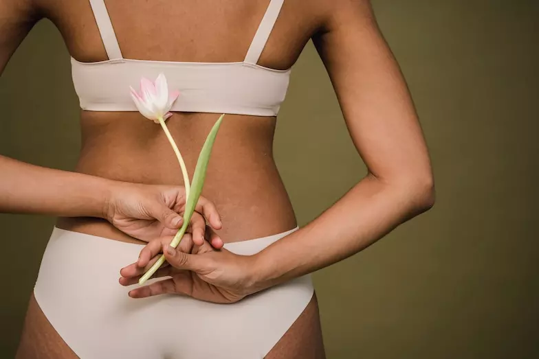ragazza di schiena con fiore tra le mani (trattamento ayurvedico anticellulite)