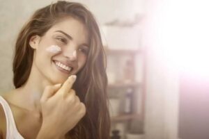 ragazza si mette una crema sul viso di un prodotto naturale